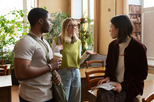 Diverse university students discussing studying in library