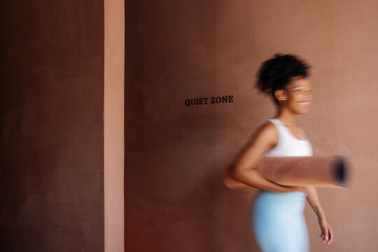Smiling Woman Carrying Yoga Mat In Quiet Studio