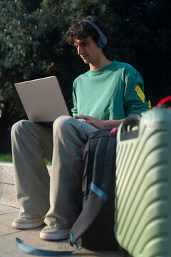 Gen z guy works on laptop while waiting in Italy