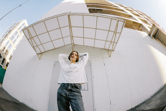 Woman Poses in Front of Building During Sunny Day in City