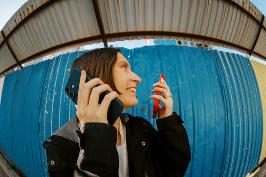 Young Woman Talks on Two Phones in Urban Setting
