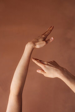 Minimal Hands Reaching Gesture Over Warm Brown Background