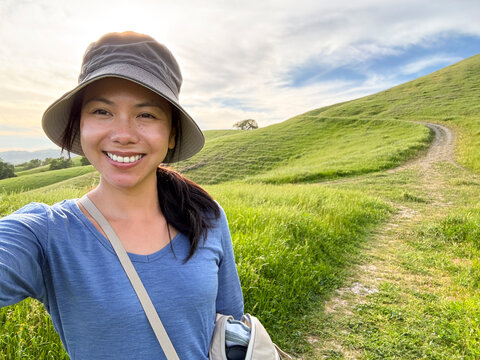 ugc selfie of asian hiker on hillside trail nature hike alone