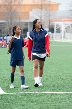 Two Girls Walk on a Soccer Field at Practice in the Afternoon