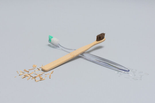 Bamboo and plastic toothbrushes crossed front view eco concept on gray background horizontal