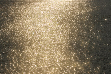 Golden sunlight reflections shimmer across rippling water, creating an elegant abstract nature background with sparkling highlights, warm tones and luxurious visual texture. © The Dell Shot by SJ