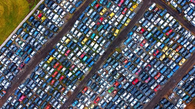 Diagonal aerial composition of densely packed old vehicles. High angle diagonal shot of numerous colorful cars arranged in geometric rows at scrapyard.