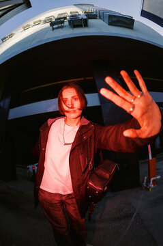 Person Waves Hand in Urban Setting During Evening Hours