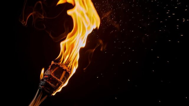 Bright flaming torch burning with sparks on black background for fire light and power concept