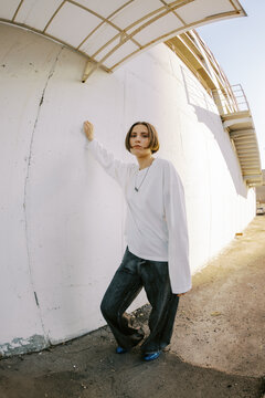 Young Person Stands by Wall in Urban Area During Daytime