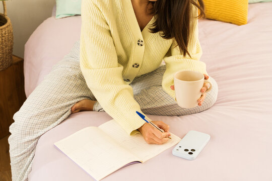 Writing notes in a cozy bedroom with coffee and a phone nearby