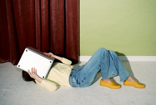 Person Lying on Floor Holding Laptop Like Book Indoors