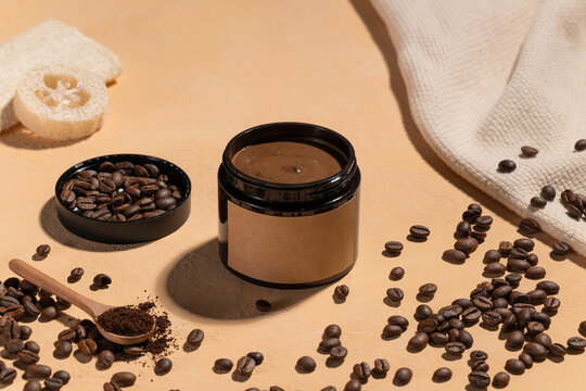 Natural coffee scrub in a jar with scattered beans and a loofah sponge