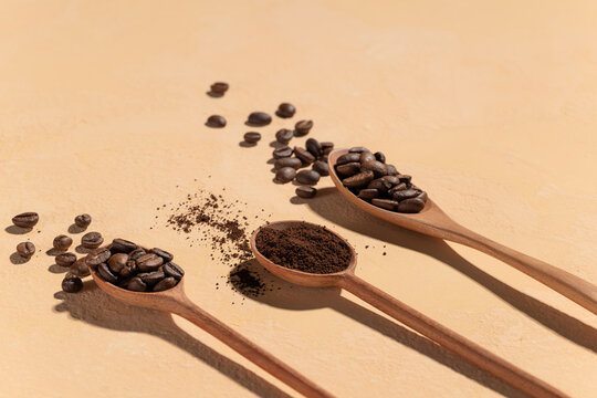 Three wooden spoons display whole roasted coffee beans