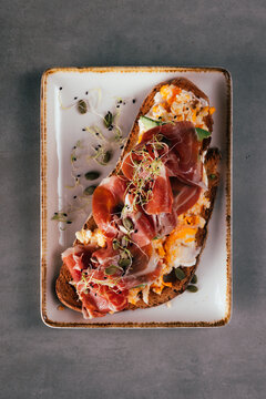 Toast with prosciutto, scrambled eggs, shoots and seeds