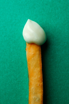 a close-up of a french fry with mayonnaise on a green background