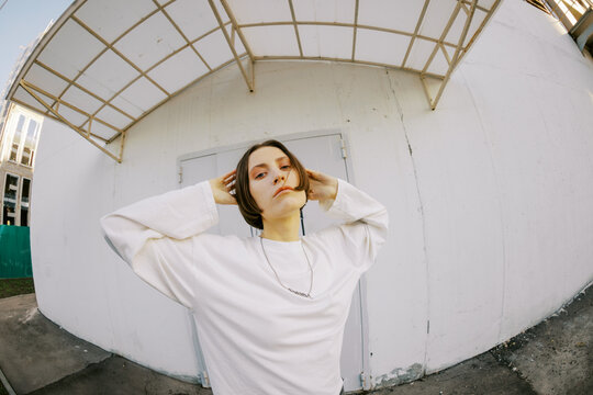Young Person Standing Against a White Wall in an Urban Area