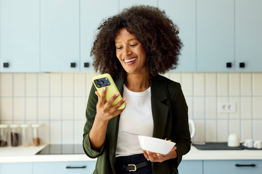 Woman smiles while using phone in the kitchen
