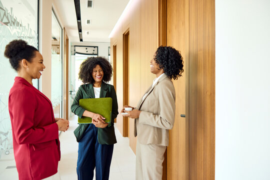 Women converse in a company's hallway.