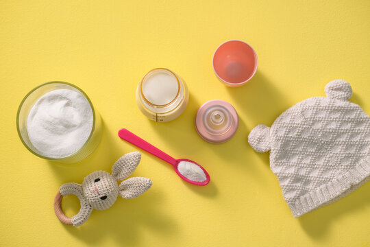 Baby care essentials laid out on a bright yellow background, top view