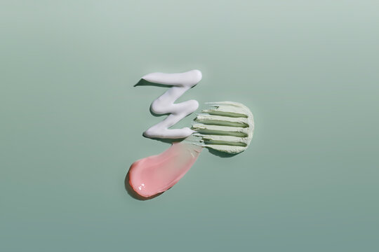 Swirls of pink and white cosmetic creams and green clay mask