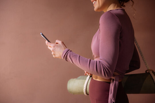 Smiling Woman Holding Phone With Yoga Mat