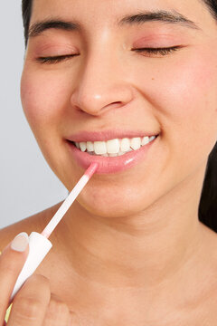 Woman applying lip gloss during natural beauty routine