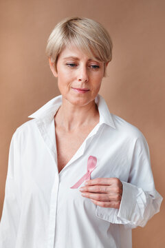 Woman Proudly Displays Pink Ribbon in a Soft, Warm Setting