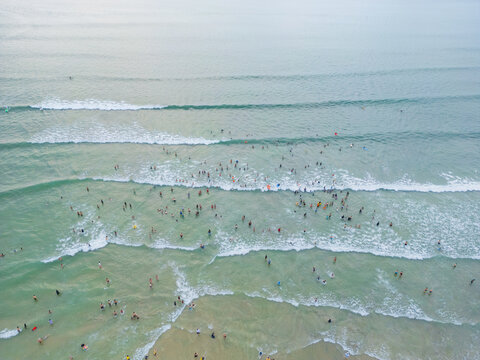 Crowds of people swimming and playing in shallow waves on the beach