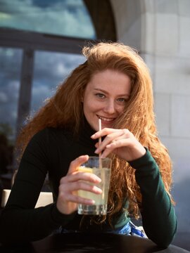 Young Woman Enjoys Drink at Outdoor Cafe During Sunny Day