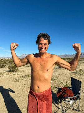 Man Flexing After Shower in Desert Camp