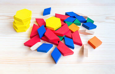 Colorful wooden geometric shapes including hexagons, squares, and triangles scattered on a light wooden surface, ideal for educational play and learning activities © Nizoli