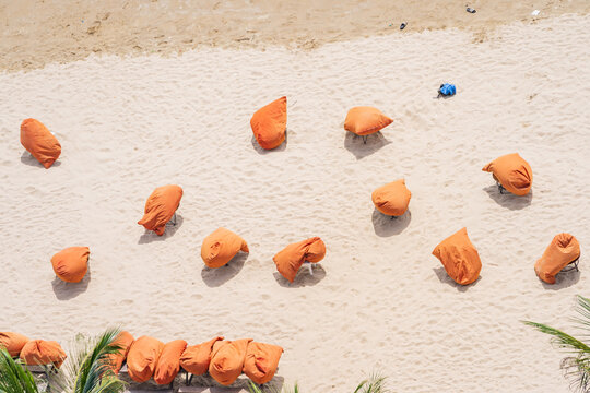 Bright orange bean bags scattered along a sandy beach