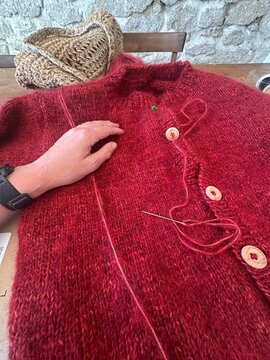 UGC Hand of woman sewing buttons on knitted cardigan