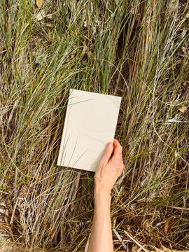 Hand holding blank book in beach grass