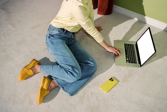 Person Sitting on Floor Using Laptop with Smartphone Nearby