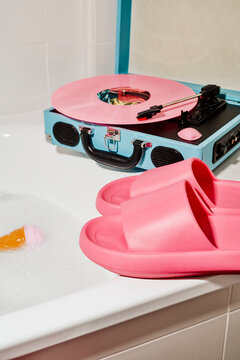 pink slides on a bathtub edge near a turntable playing a record