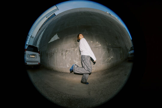 Person Walks in Casual Clothes Against a Wall in a City Area
