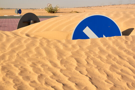 Roundabout road traffic signs buried by sand dune desertification