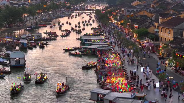 Hoi An city in Vietnam. Aerial Drone Flight at Sunset Time showcasing river with boats, street traffic and old buildings