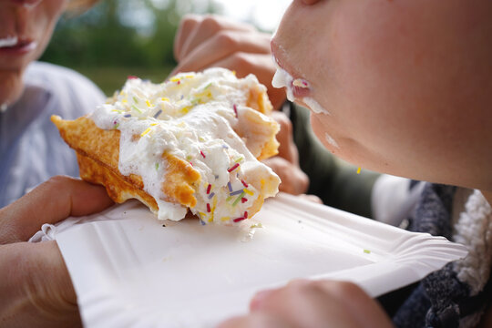 Person enjoying a fresh waffle with whipped cream and sprinkles, close-up shot