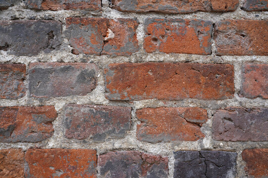 Weathered red brick wall texture with rough cement joints in historic Orleans France