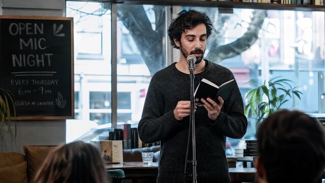 Young Man Reading Poetry at Open Mic Night in Local Cafe