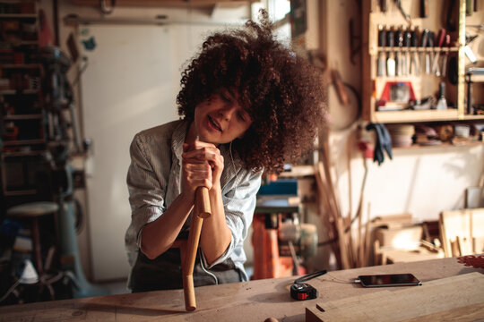 Woman woodworker shaping wooden dowel in workshop