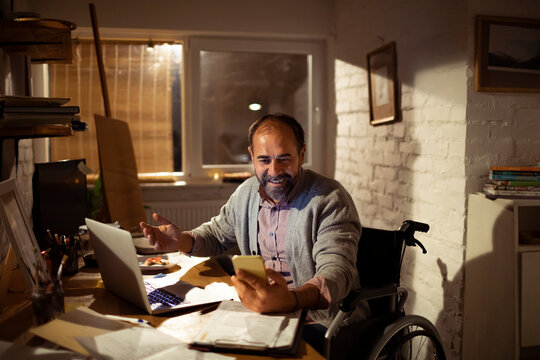 Smiling man in wheelchair on video call at home office