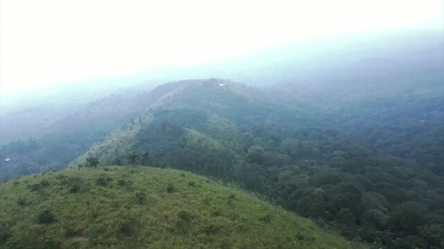 Aerial 4k view of beautiful misty green hills, grassy valleys, and tropical mountain forest.
