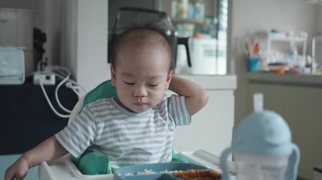 A joyful baby sits in a high chair, savoring a colorful meal at home. The scene captures the essence of family life, with a cozy kitchen backdrop enhancing the warm atmosphere.
