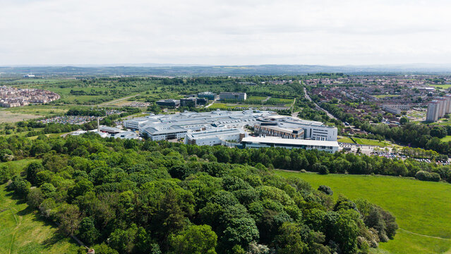 Beautiful aerial panorama of a modern hospital and medical campus in Edinburgh, Scotland. Scenic city landscape with contemporary architecture surrounded by lush green trees and summer fields.
