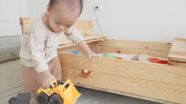 A joyful young child is engaged in playtime with various colorful toys in a wooden box. The cheerful atmosphere captures the essence of childhood fun and creativity.