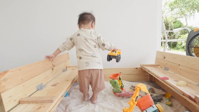 A young child explores a vibrant sandbox filled with toys, fostering creativity and imagination. This playful environment encourages sensory experiences and outdoor fun.